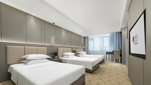 Ein Hotelzimmer mit zwei Betten, einem Schreibtisch und einem großen Fenster.