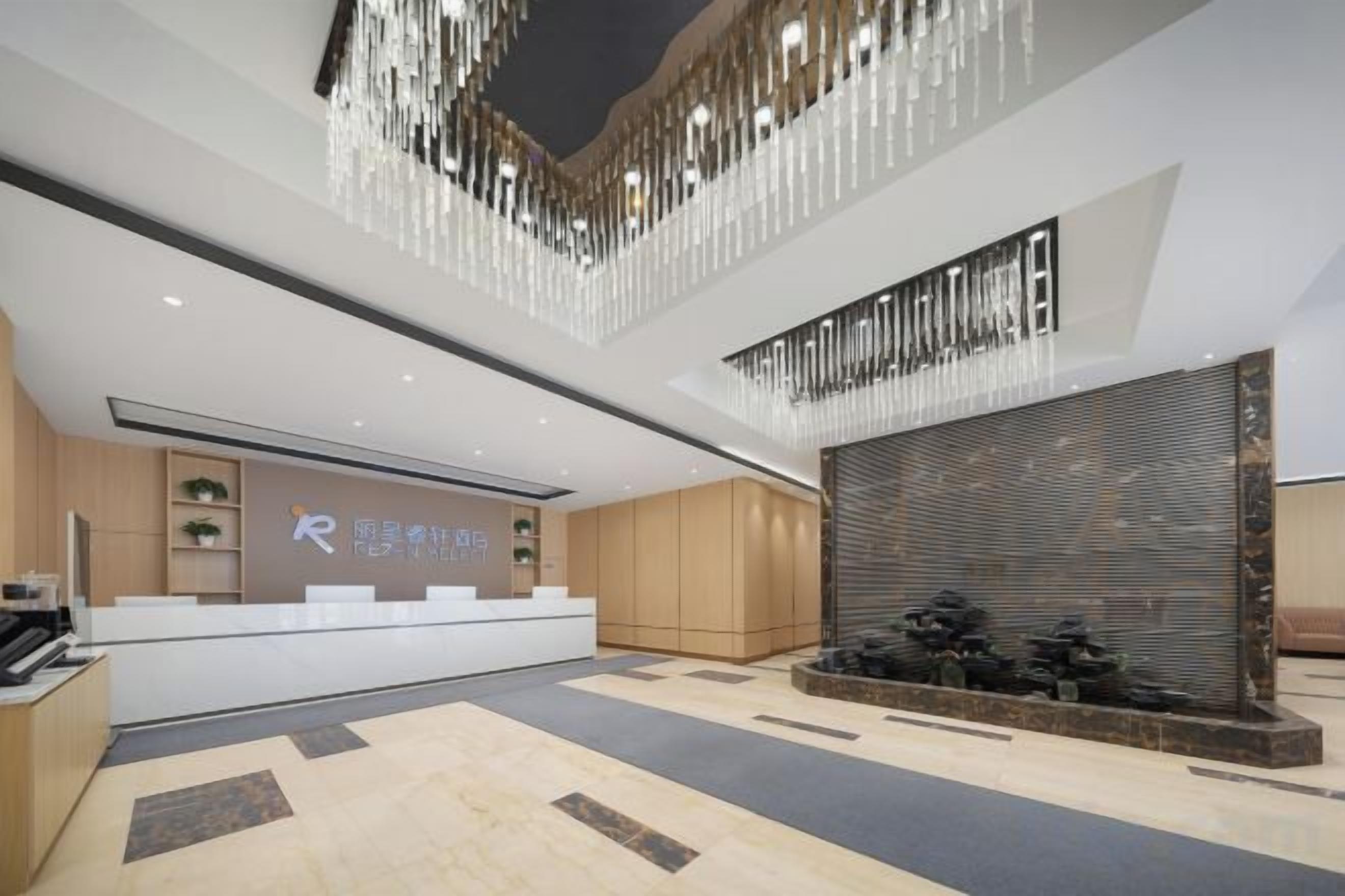 A modern hotel lobby with a reception desk, seating area, and decorative elements.