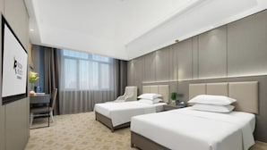 Ein Hotelzimmer mit zwei Betten, einem Schreibtisch und einem Stuhl.