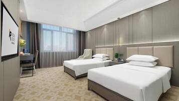 A hotel room with two beds, a desk, and a chair.