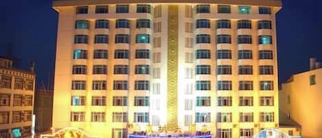 A multi-story hotel with a central atrium and a well-lit facade.