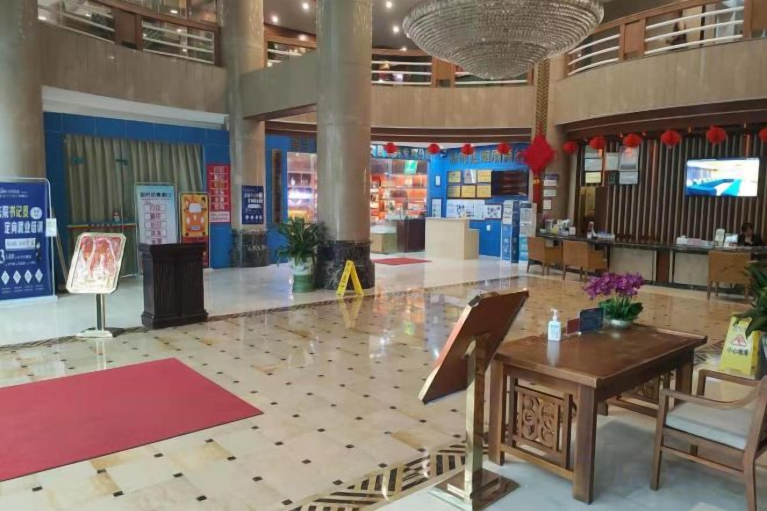 A spacious lobby with a reception desk, seating area, and a large chandelier.