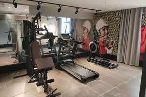 Un gimnasio con diverso equipo de ejercicio, incluyendo cintas de correr, una prensa de banca y una máquina de pesas.