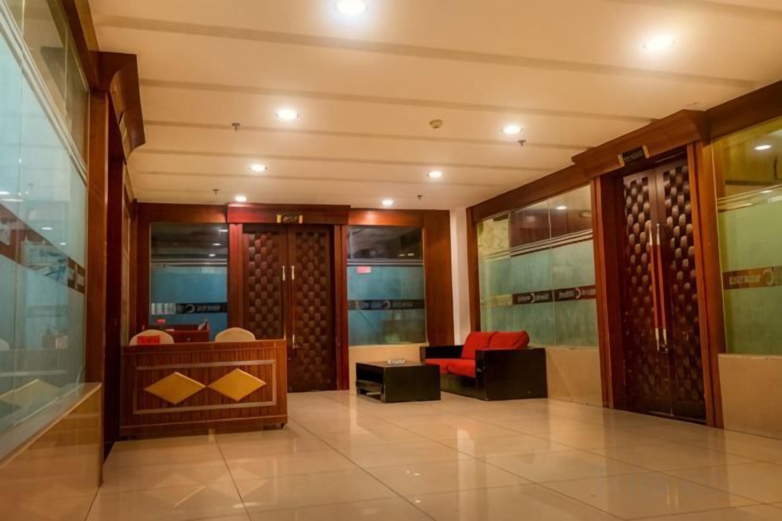 A hotel lobby with a reception desk, seating area, and a large wooden door.