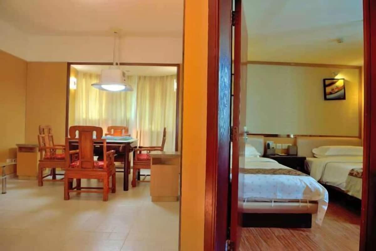 Habitación de hotel con cama, escritorio con sillas, zona de comedor y vistas al exterior.