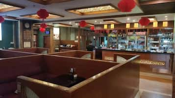 Restaurante com cabines, área de bar e lanternas vermelhas.