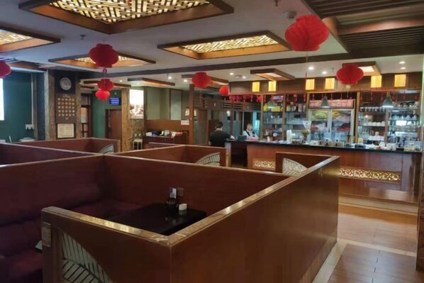 Un ristorante con cabine, un'area bar e lanterne rosse.