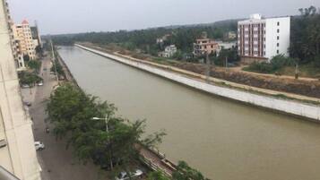 A river running alongside a road with buildings on one side.