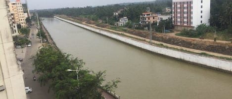 Une rivière qui longe une route, avec des bâtiments d’un seul côté.