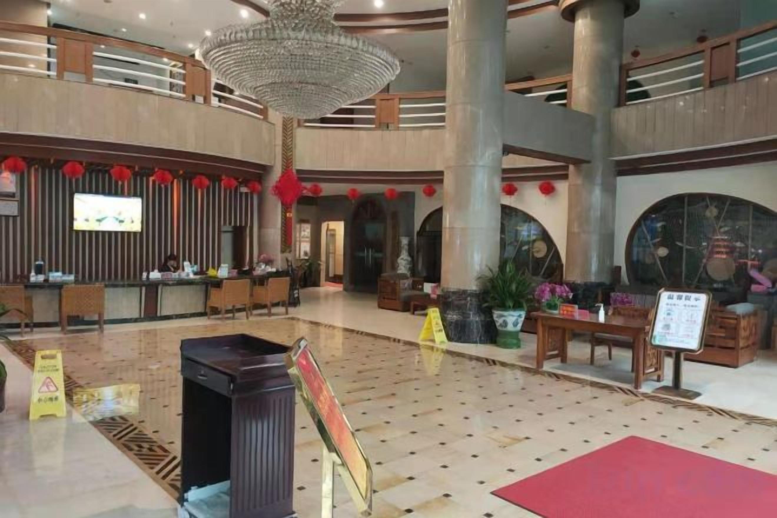 A spacious lobby with a reception desk, seating areas, and a large chandelier.