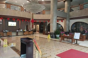 A spacious lobby with a reception desk, seating areas, and a large chandelier.