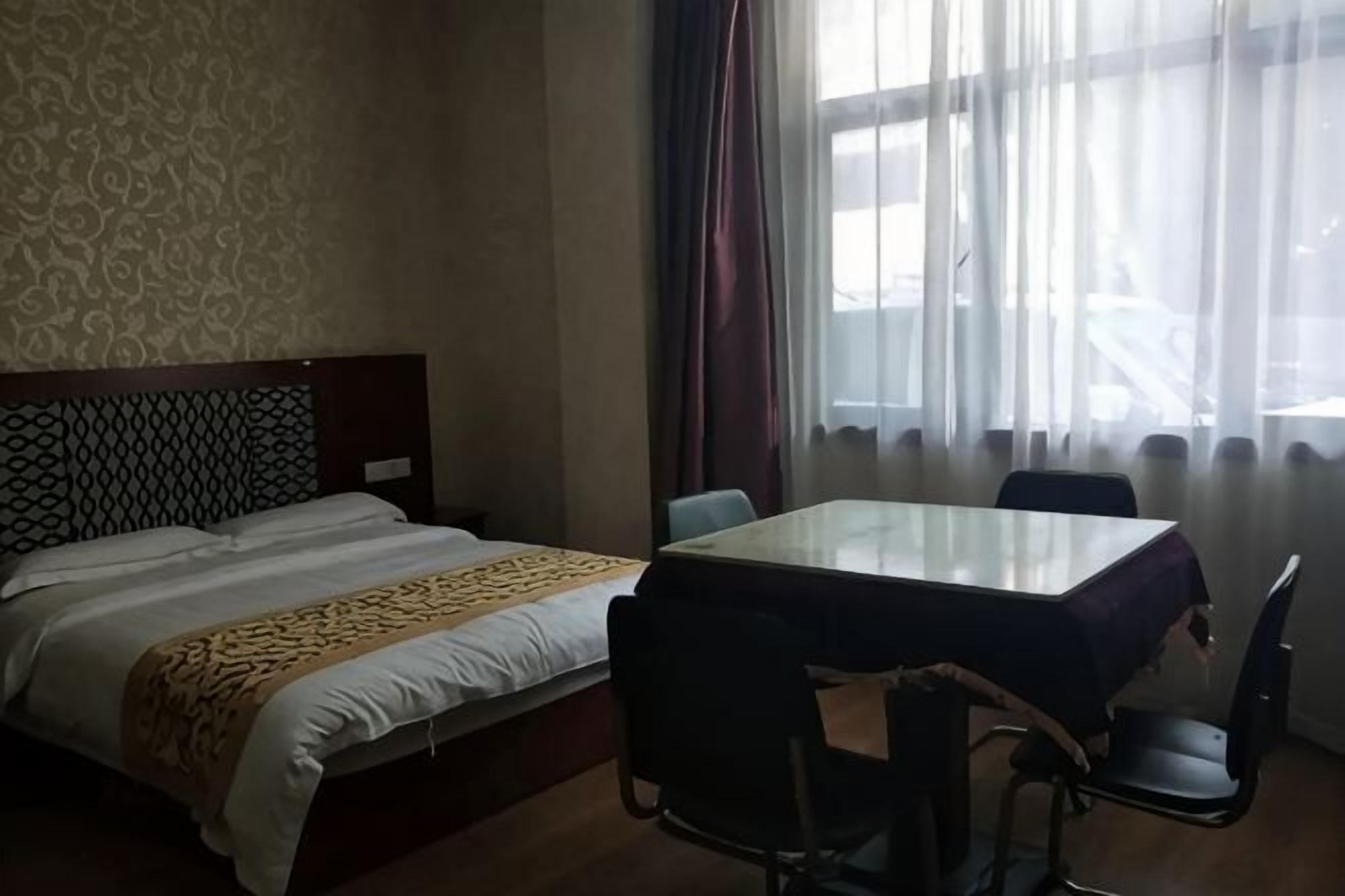 A hotel room with a bed, a table, and chairs.