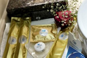 Une salle de bain avec un comptoir en marbre, un bouquet de fleurs et des articles de toilette rangés dans un sac jaune.