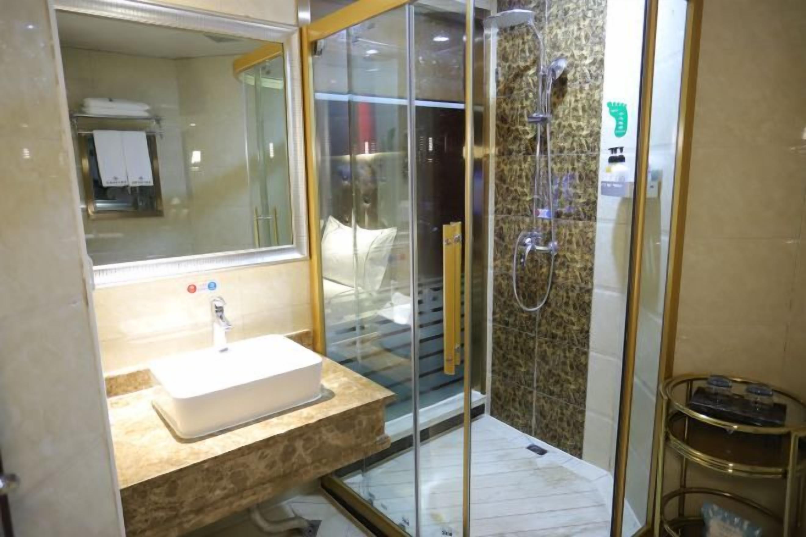 A modern bathroom with a glass-enclosed shower, a sink with a marble countertop, and a mirror.