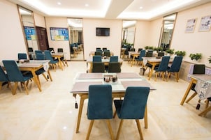 Un salón de conferencias con mesas y sillas, un televisor de pantalla plana y un espejo grande en la pared.