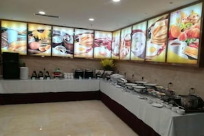 Montaje tipo bufé con diversos alimentos y una pared grande mostrando imágenes de comida.