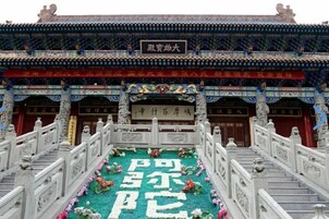 Edificio chino tradicional con arquitectura ornamentada, una escalera central y un arreglo floral con caracteres chinos.