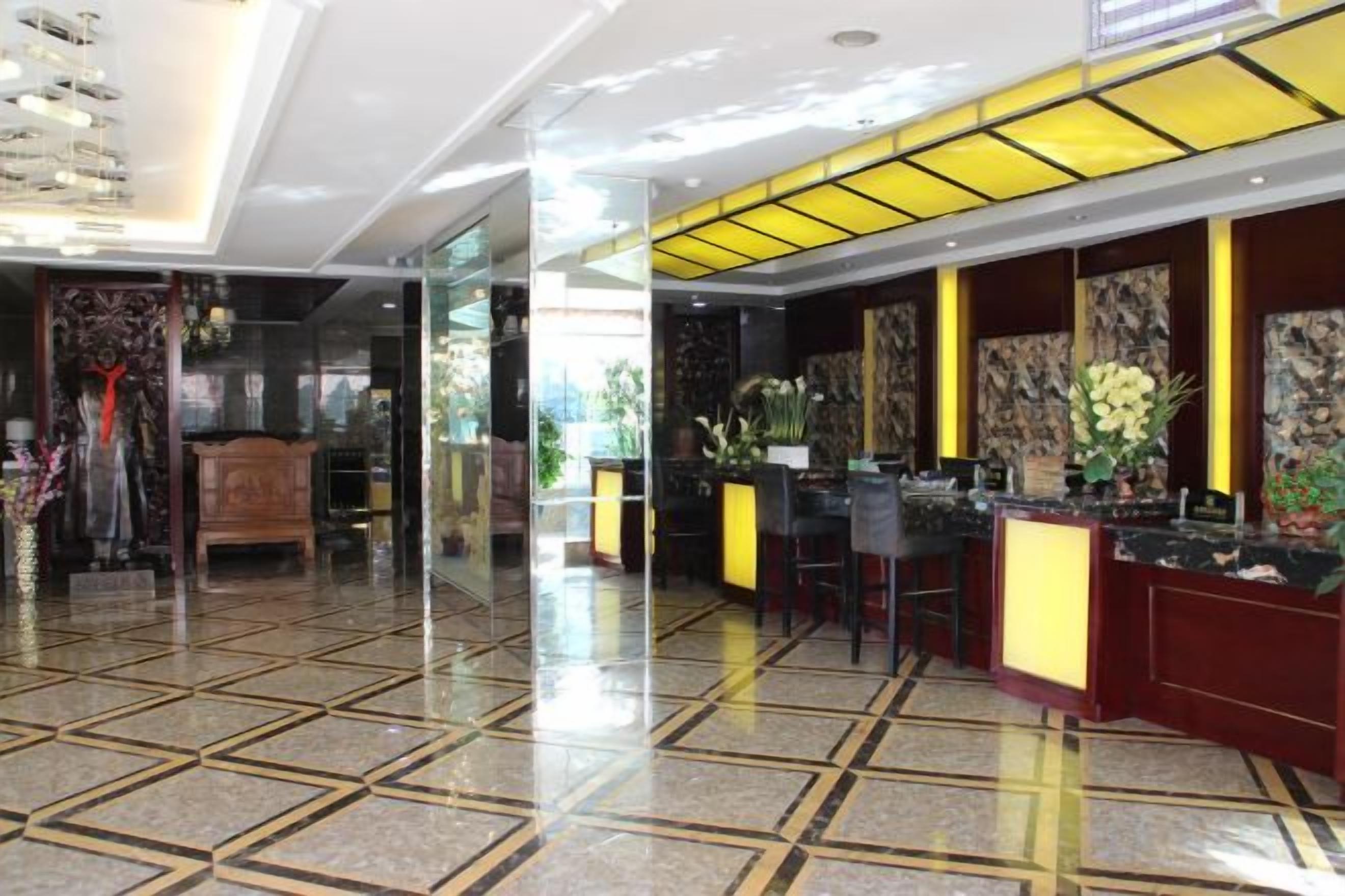 A hotel lobby with a reception desk, a seating area, and a decorative wall.