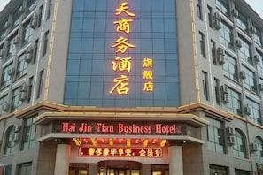 Um hotel com uma placa destacada em caracteres chineses e texto em inglês indicando ser o Hai Jin Tian Business Hotel.