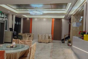 A hotel lobby with a reception desk, round tables, and chairs, a staircase, and a chandelier. - HFDJD (Xinyuan)