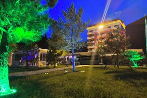 A building with multiple floors, a parking area, and trees.