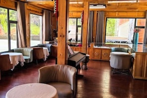 Un intérieur en bois avec des tables et des chaises, un piano et de grandes fenêtres.