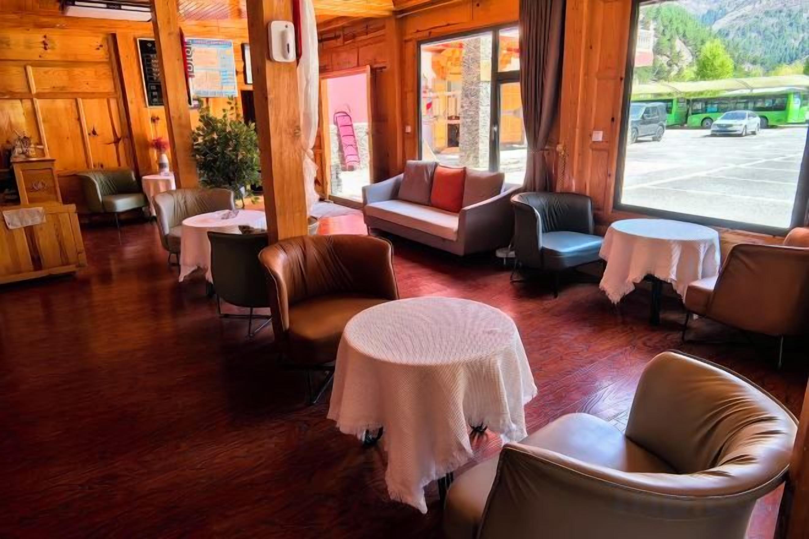 A cozy interior with wooden walls, leather sofas, and round tables with white tablecloths.
