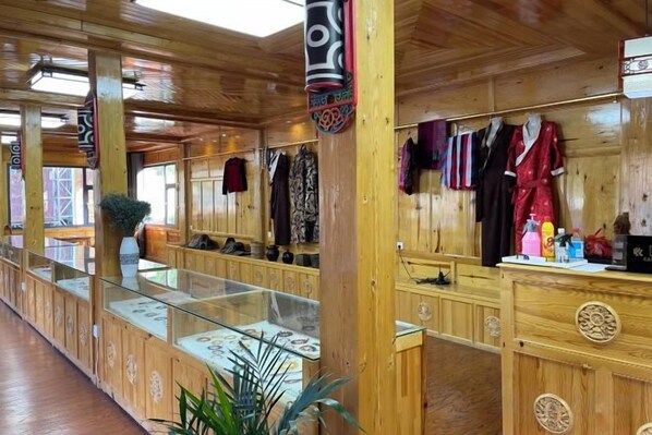 Un interior de madera con una mesa de recepción, vitrinas de vidrio y percheros.