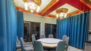 Un salón de conferencias con una mesa redonda, sillas y cortinas.