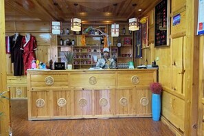 Zona de recepción con mostrador de madera, una recepcionista y una exhibición de diversos objetos.