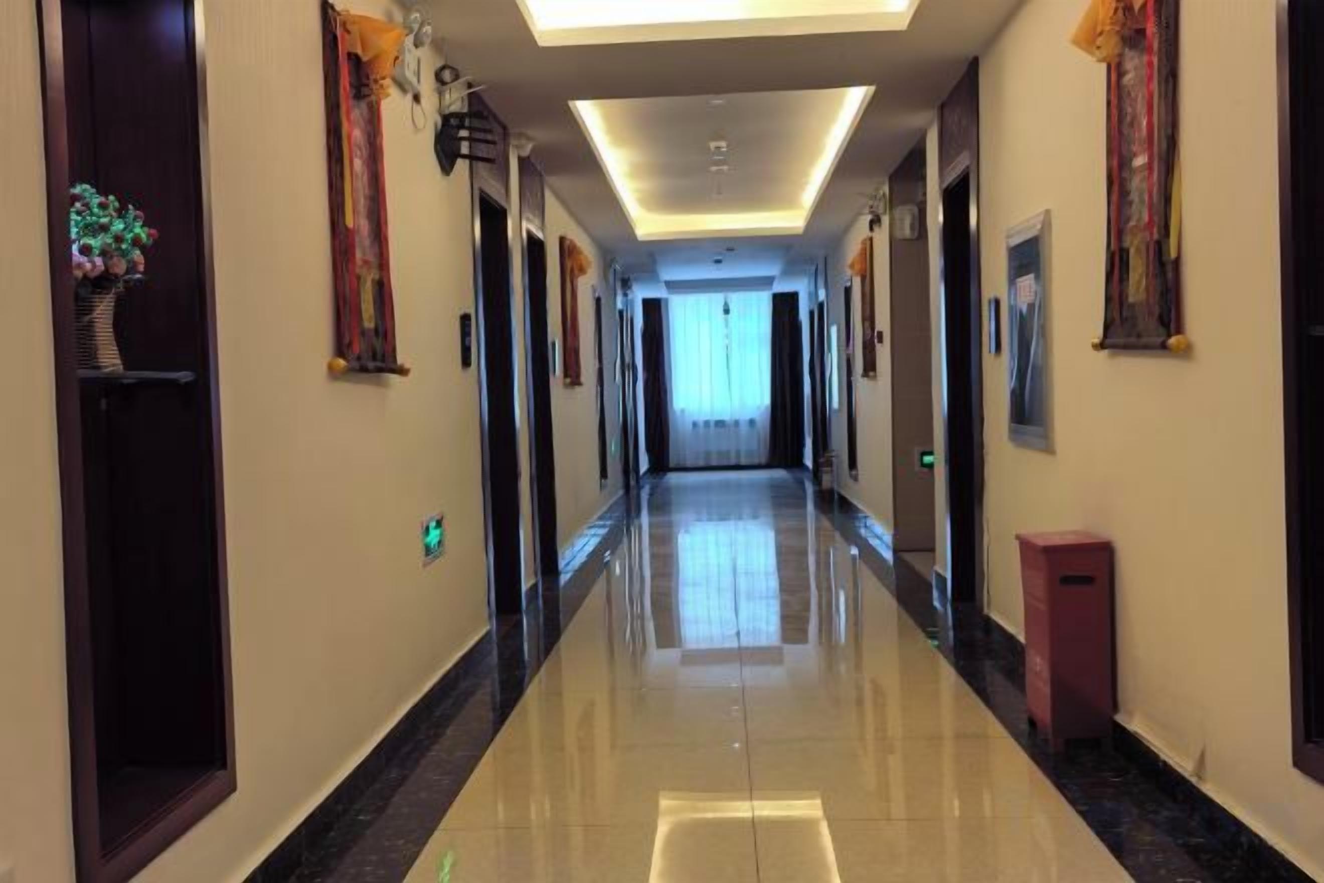 A hotel corridor with doors on both sides, a trash bin, and a light fixture on the ceiling.