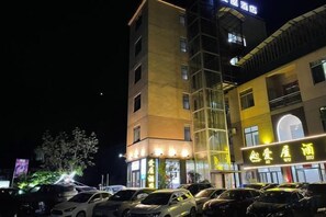 A multi-story hotel with a parking lot in front. - Aiwu Inn Daxin County Detian Waterfall (Daxin)