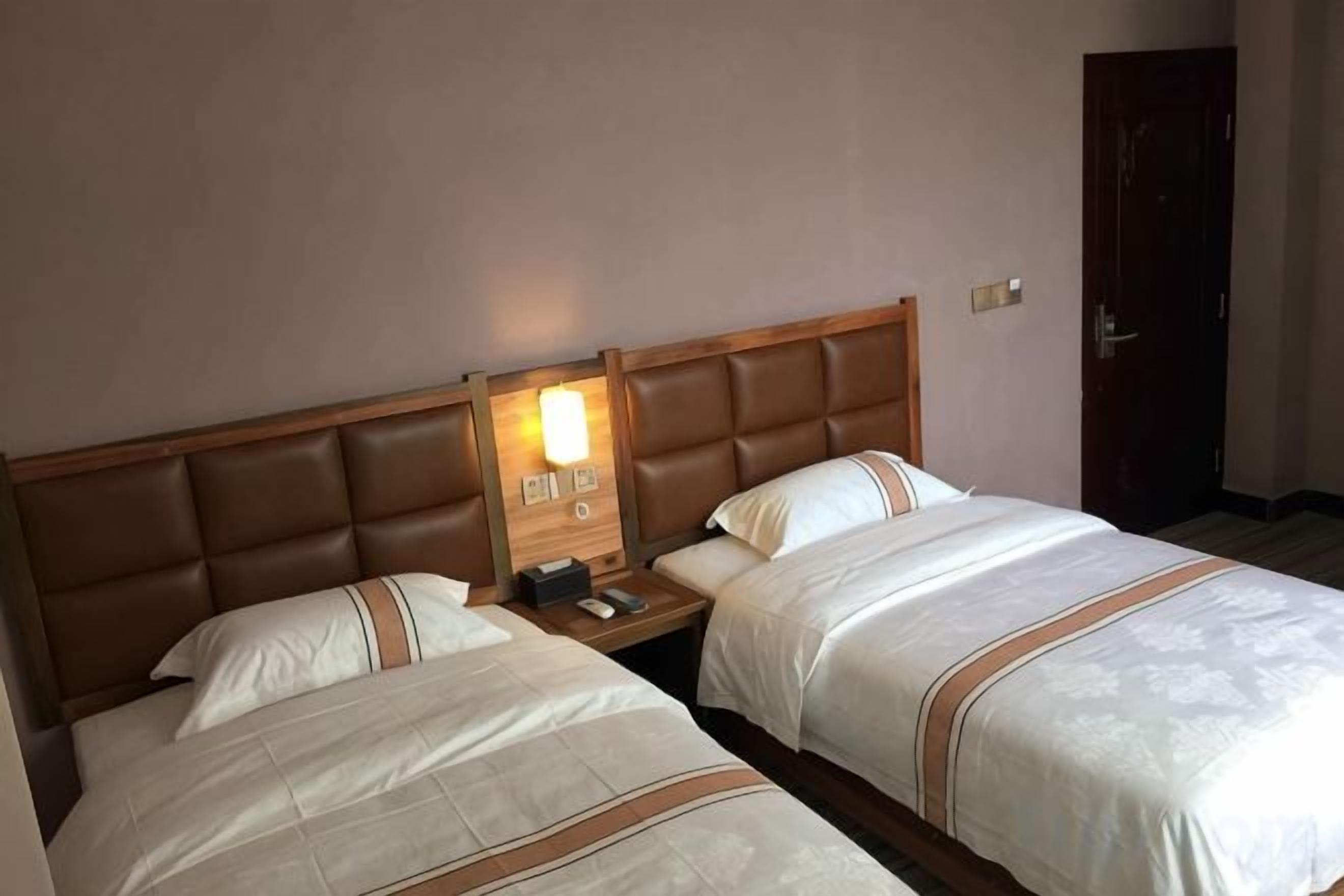 Ein Hotelzimmer mit zwei Betten, einem Nachttisch und einer Wandleuchte.