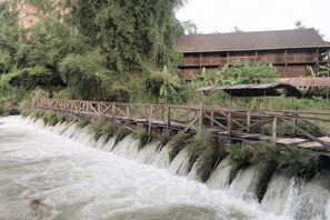 A wooden bridge over a waterfall with a building in the background. - Aiwu Inn Daxin County Detian Waterfall (Daxin)
