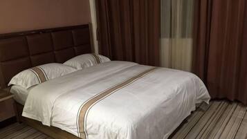 Una habitación de hotel con una cama, una mesita de noche y una ventana con cortinas.