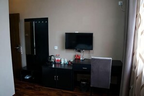 A room with a bed, a desk, a chair, a television, and a mirror. - Haopai Hotel (Shanghai)