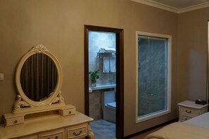 Una camera da letto con un'ampia finestra, una toeletta con specchio e un ingresso che conduce al bagno.