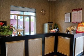 A reception desk with a window, a clock, and a framed notice on the wall. - Haopai Hotel (Shanghai)