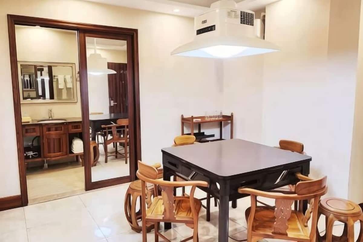 A dining area with a table and chairs, a mirror, and a sliding door leading to a bathroom.