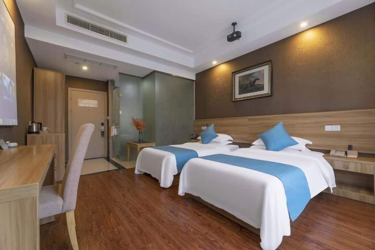 A hotel room with two beds, a desk, and a chair.