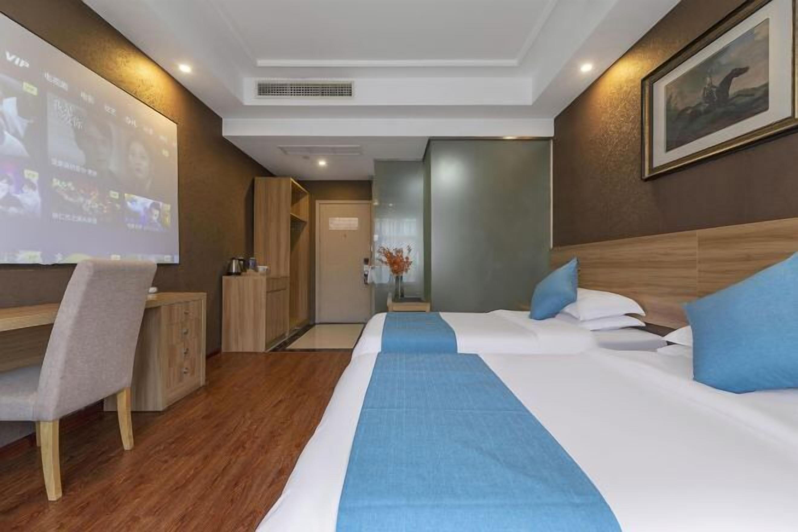 Ein Hotelzimmer mit Bett, Schreibtisch, Sessel, Fernseher und einer Tür.