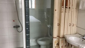 A bathroom with a toilet, a shower, and a sink. - Fanchang Yichun Hotel (Wuhu)