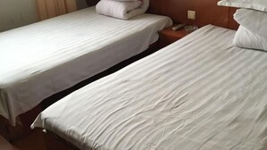 Two single beds with white linens, wooden headboards, and a nightstand with a glass bowl. - Fanchang Yichun Hotel (Wuhu)