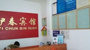 A reception desk with a red sign above it and several notices on the wall. - Fanchang Yichun Hotel (Wuhu)