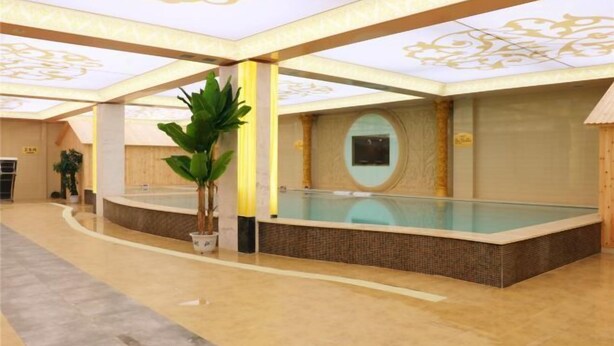 A modern indoor swimming pool with a glass enclosure, surrounded by a tiled floor and a decorative ceiling. - YinXiang changchun (Huixian)