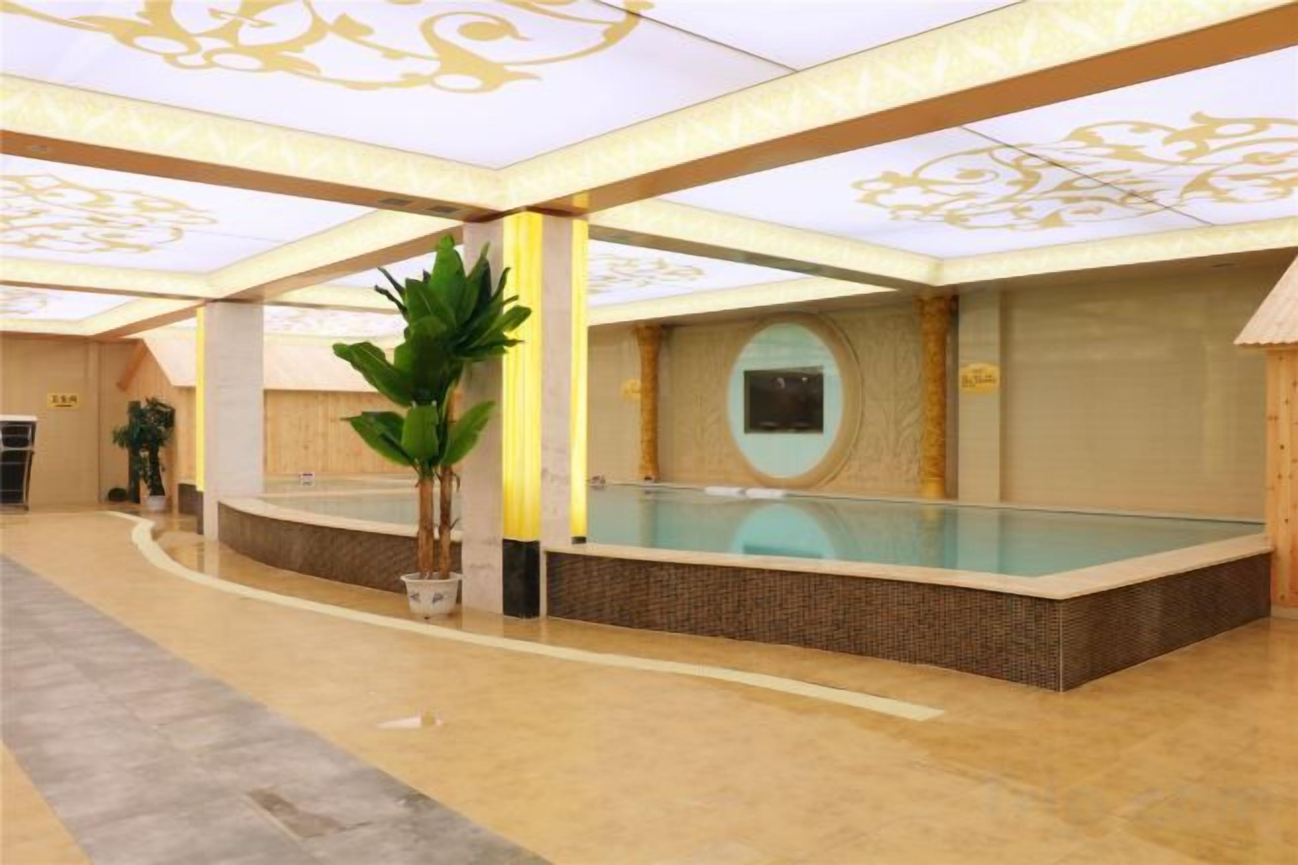 A swimming pool area with a tiled floor, a potted plant, and a wall-mounted screen.