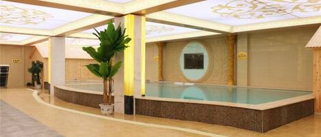 A swimming pool area with a tiled floor, a potted plant, and a wall-mounted screen.