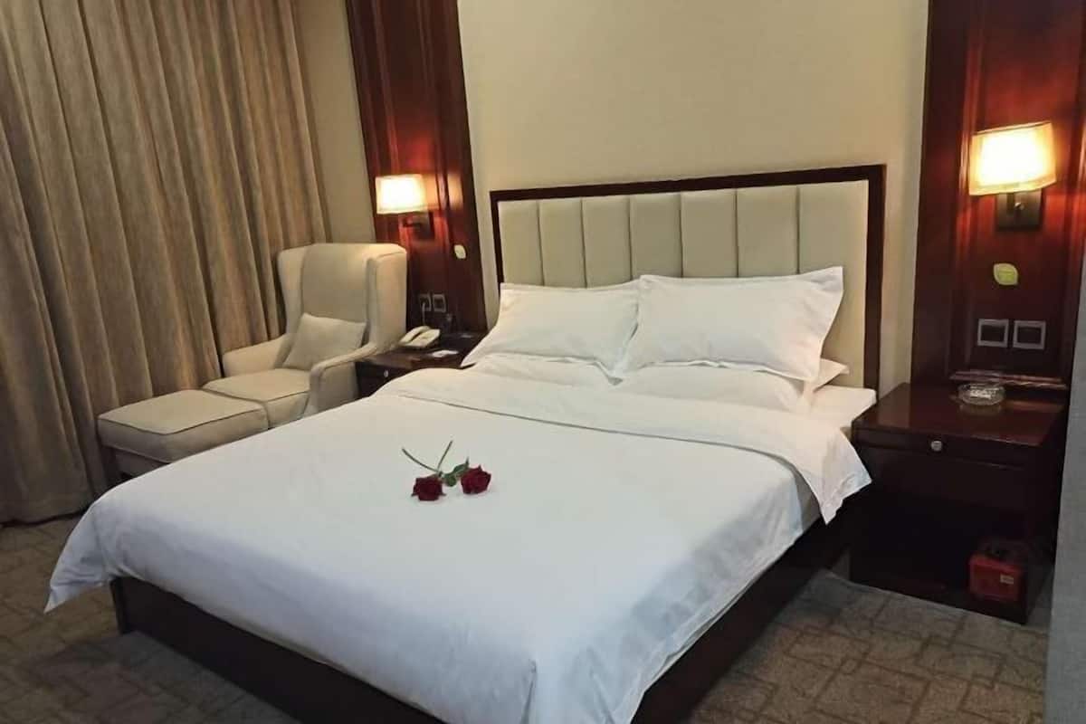 Une chambre d’hôtel avec un lit, une chaise, une table de chevet et une lampe.