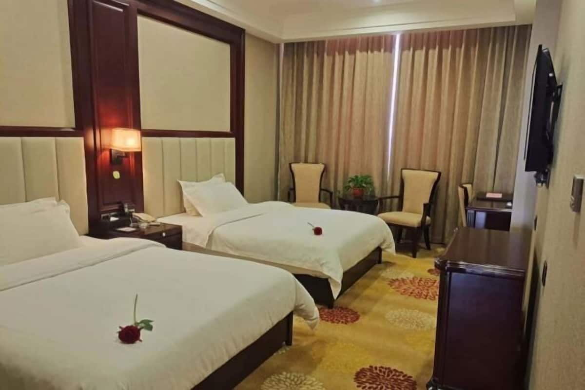 Une chambre d’hôtel avec deux lits, une télévision, un bureau et une chaise.