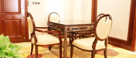 Un salón de conferencias con una mesa rectangular y cuatro sillas, una puerta de madera y una alfombra estampada.
